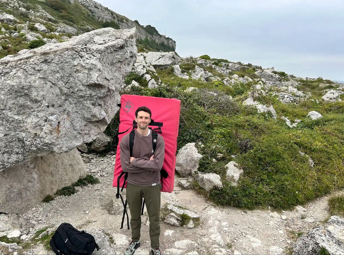 Josh Rundle carrying a crash pad outdoors